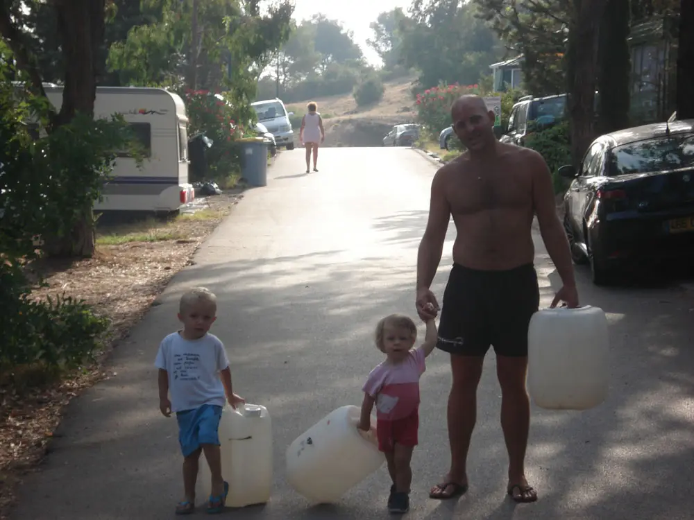 Father and his two children on their way to fill water jerrycans at Esterel Caravaning campsite