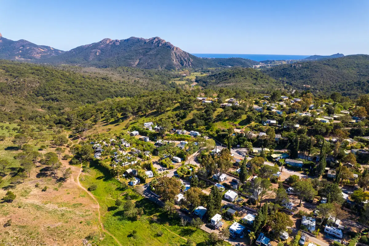 Aerial view of the Esterel Caravaning estate in Agay, its pitches beneath the pines, the Esterel massif and the sea on the horizon