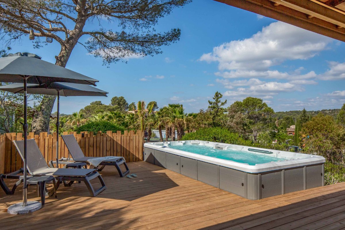 Private swim spa and sun loungers on the wooden deck of the VIP Duo at Esterel Caravaning, under the pines