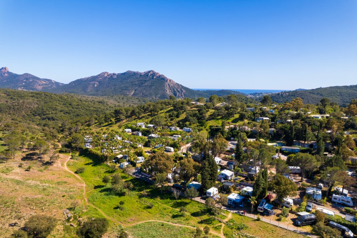 Aerial view of Esterel Caravaning in Agay, its pitches nestled in greenery and the Estérel massif in the distance